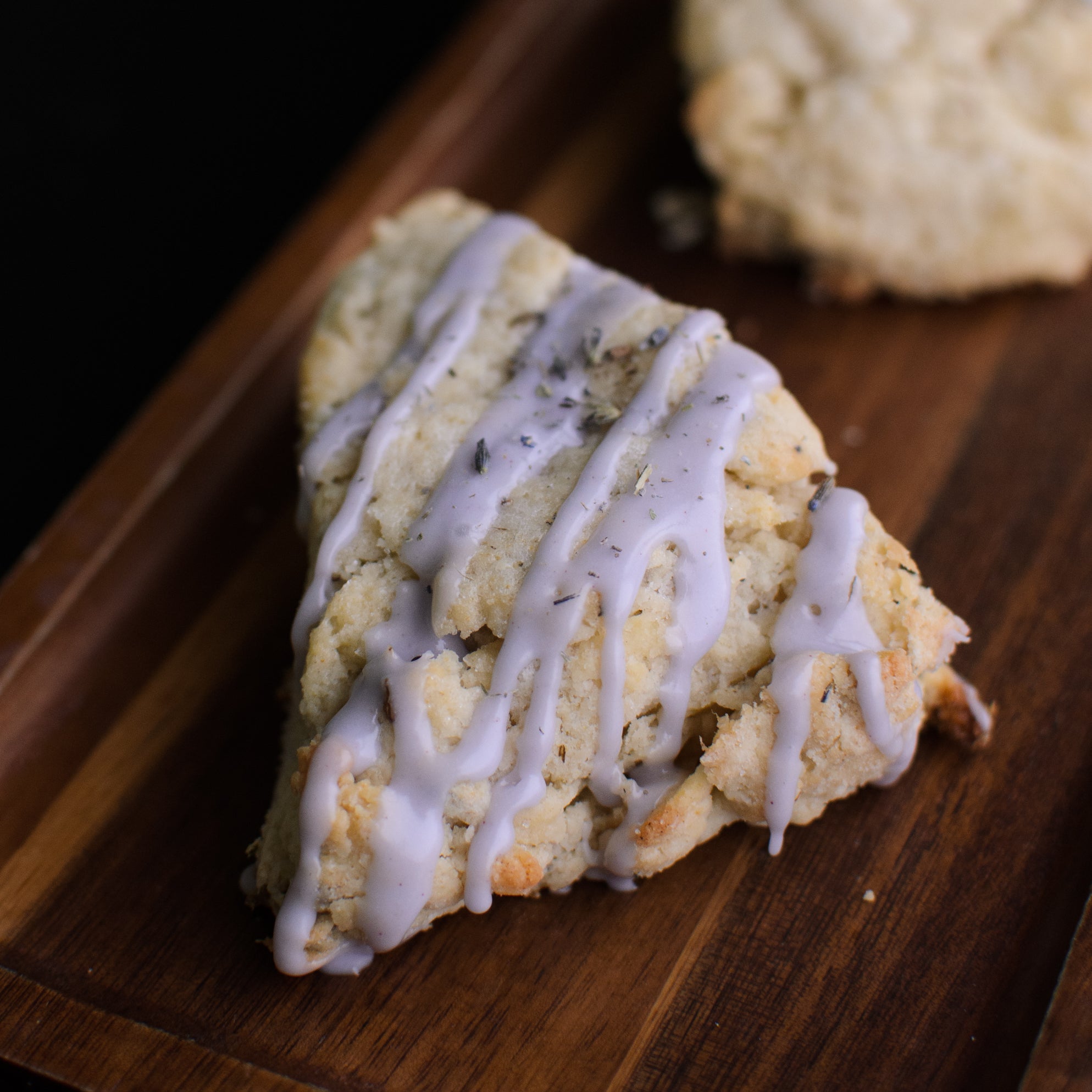 Scones with a drizzle of icing on a wooden board